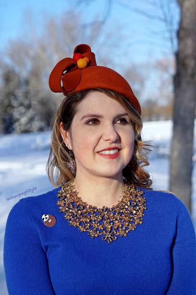 Winnipeg Style, fashion consultant, personal shopper, Coque Millinery by Ericah Rebecca orange wool pom pom winter hat, Chicwish cloud sky print midi skirt, Mary Frances beaded bird clutch purse, Leanimale sloth pin brooch, Lord & Taylor cobalt blue cashmere sweater, orange and blue color combination